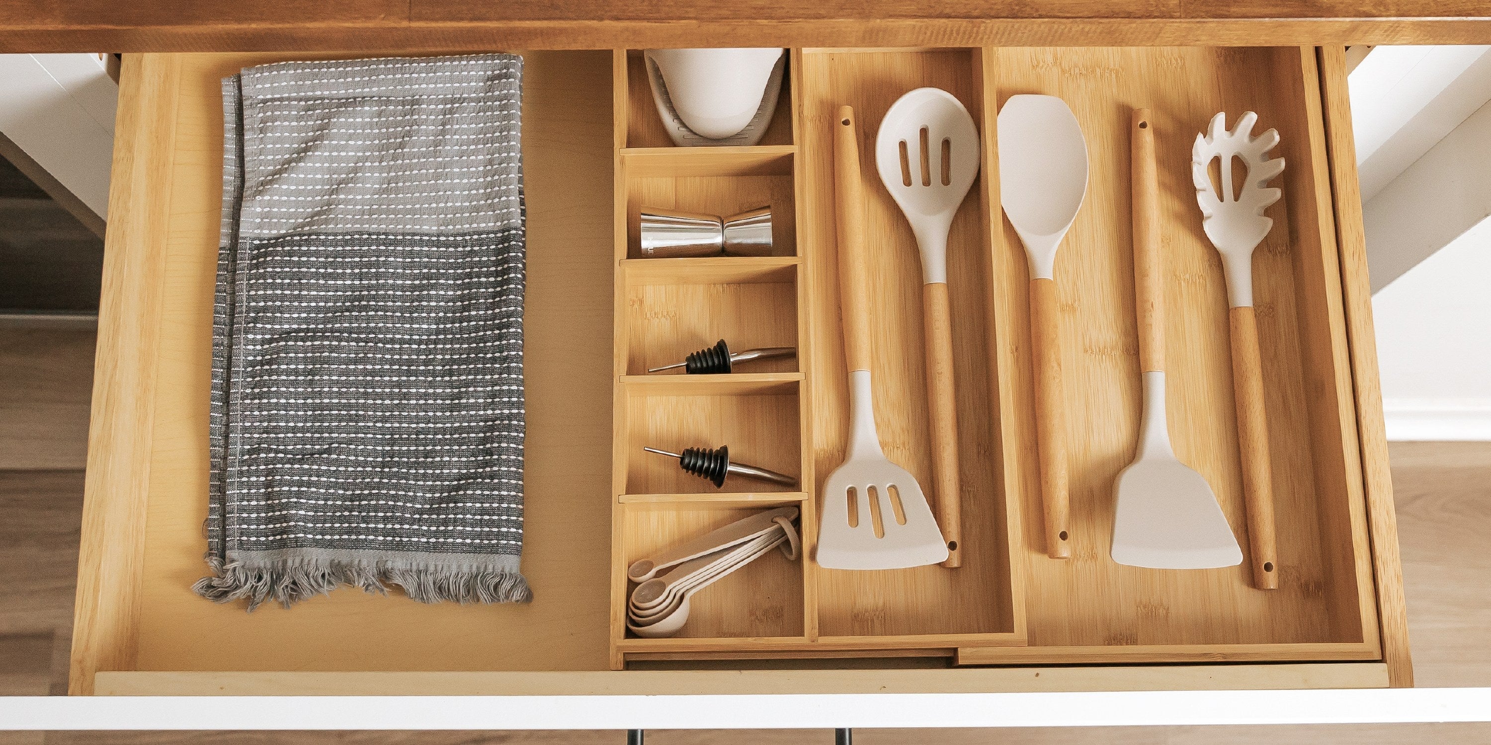 Bamboo utensils and junk drawer organizer holding small kitchen items in an open drawer