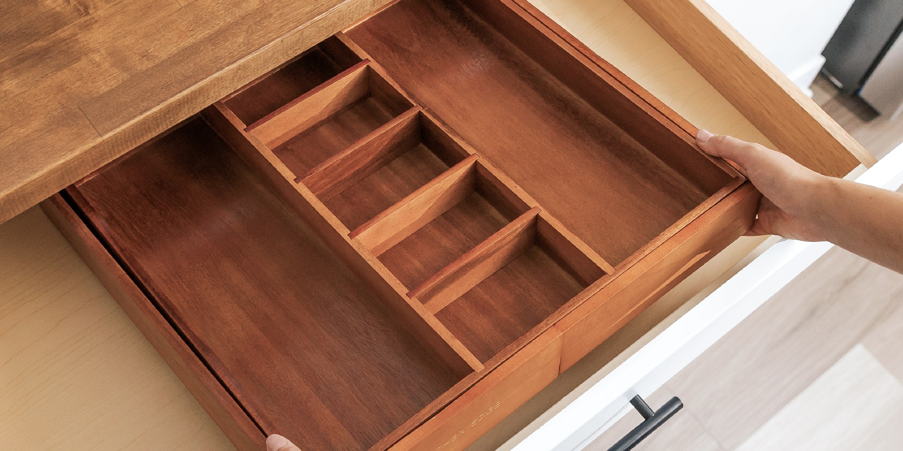 Empty acacia drawer organizer going into a kitchen drawer